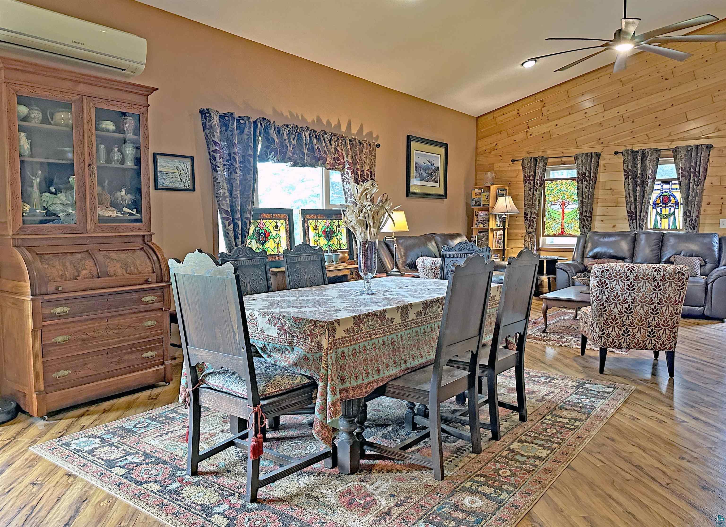 5865 Eastview Road Iron River, WI 54847 - Photo 4 of 41 Dining area with wood walls, light hardwood / wood-style flooring, lofted ceiling, ceiling fan, and a wall mounted AC