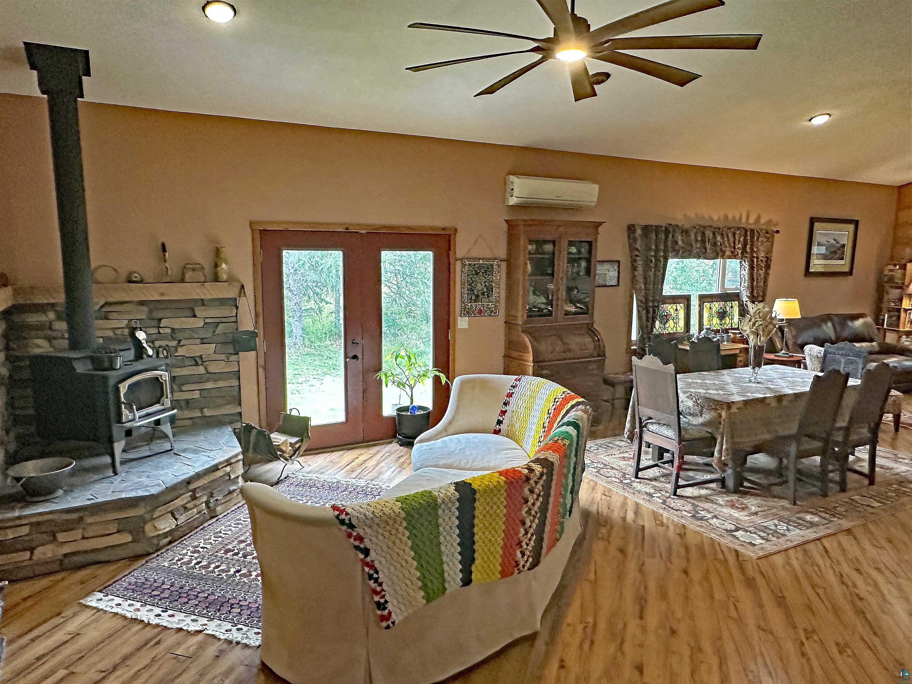 5865 Eastview Road Iron River, WI 54847 - Photo 5 of 41 Living room featuring french doors, light wood-type flooring, a wood stove, and a healthy amount of sunlight