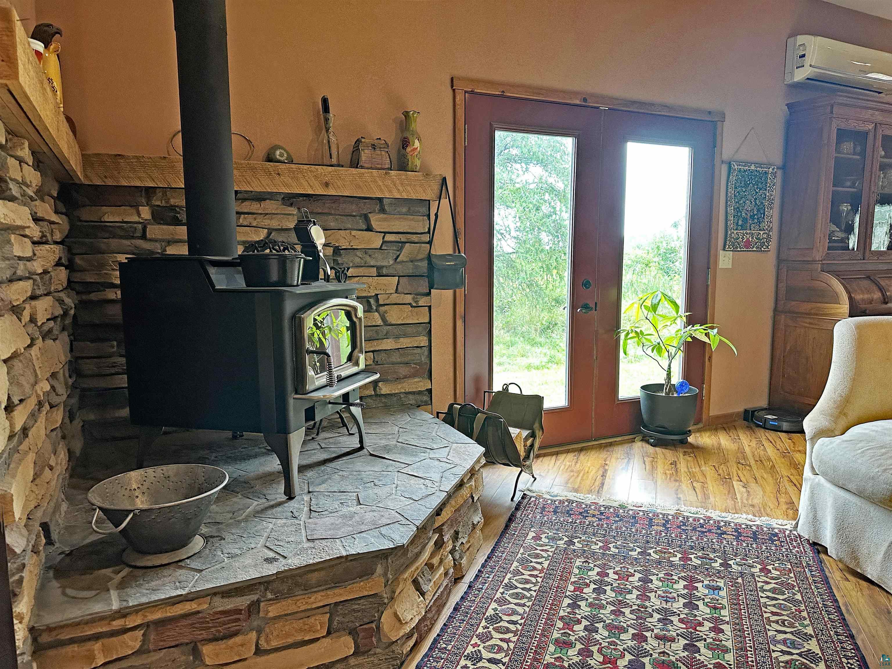 5865 Eastview Road Iron River, WI 54847 - Photo 6 of 41 Interior space with french doors, wood-type flooring, a wood stove, and an AC wall unit