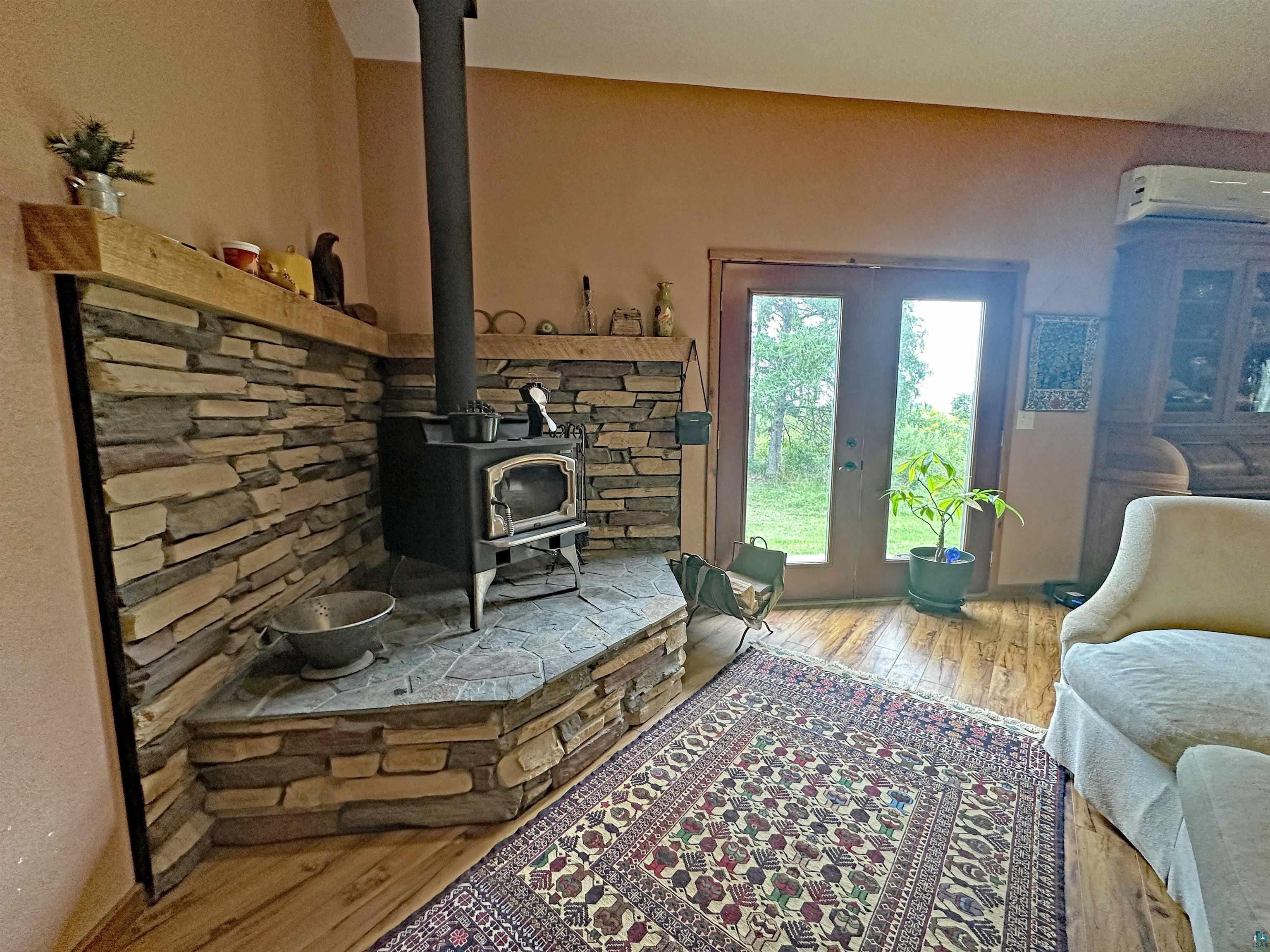 5865 Eastview Road Iron River, WI 54847 - Photo 7 of 41 Living room with a wall mounted AC, wood-type flooring, a wood stove, and french doors