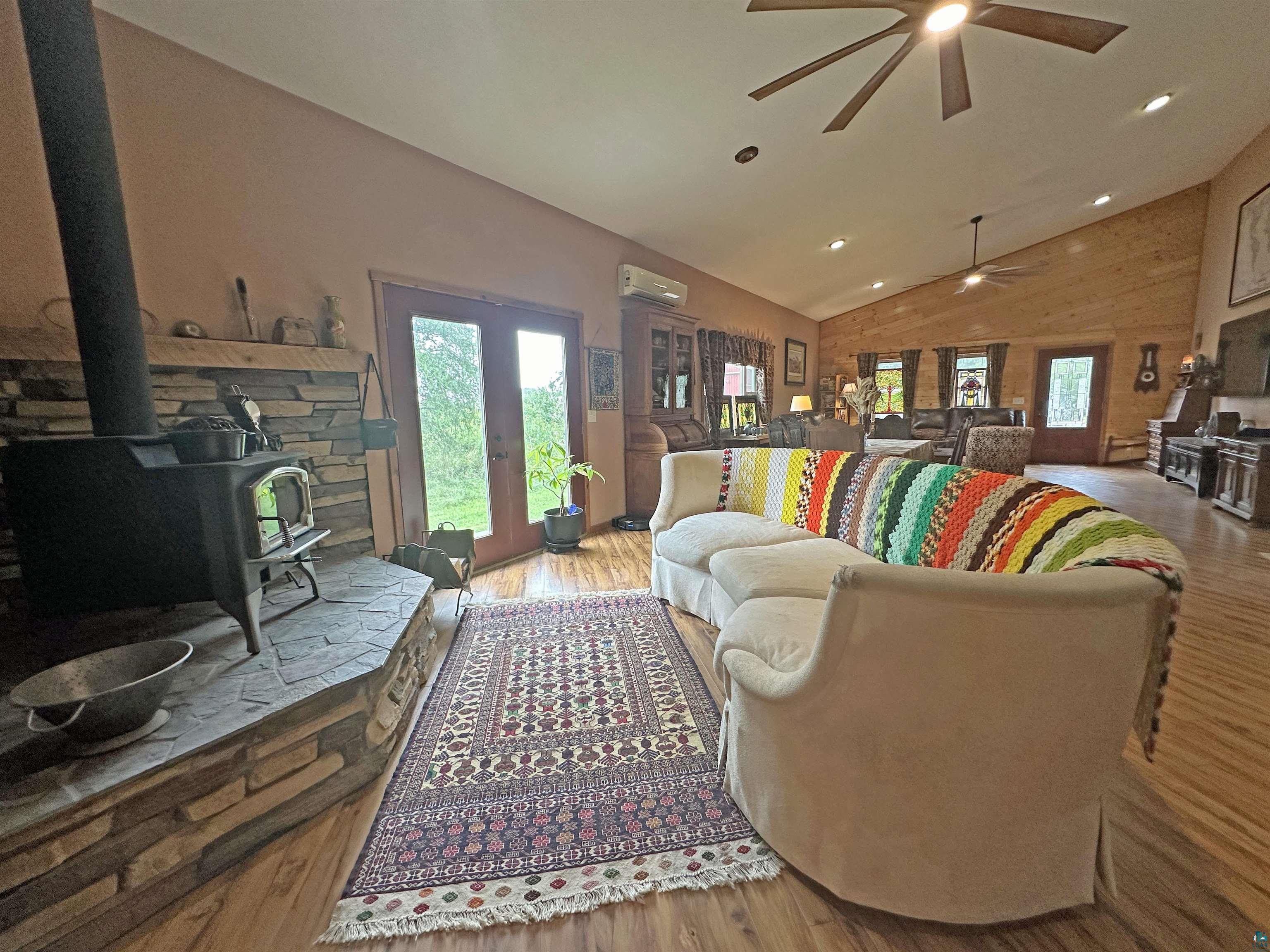 5865 Eastview Road Iron River, WI 54847 - Photo 9 of 41 Living room featuring ceiling fan, vaulted ceiling, hardwood / wood-style flooring, and a wood stove
