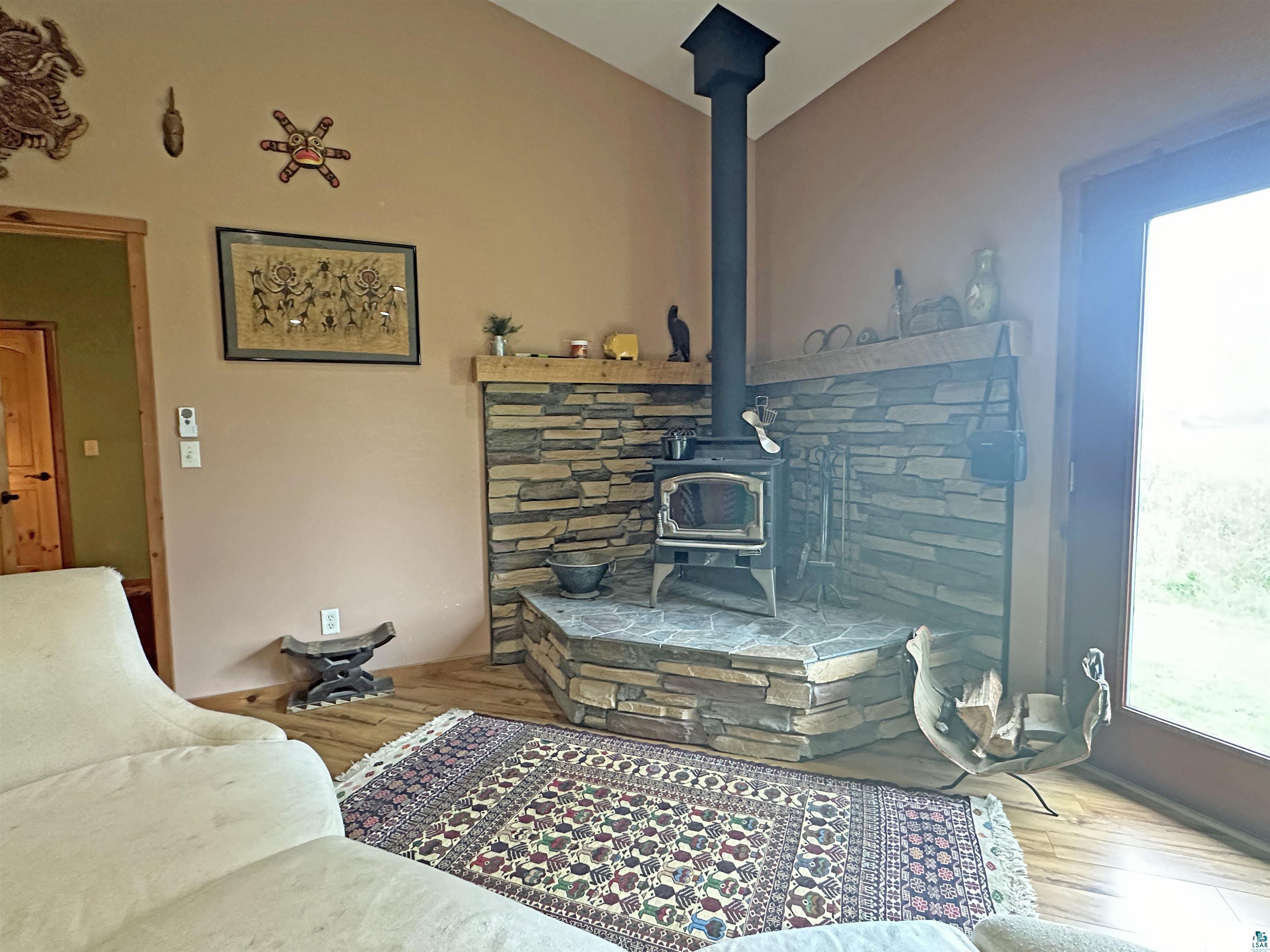 5865 Eastview Road Iron River, WI 54847 - Photo 10 of 41 Living room featuring hardwood / wood-style floors, a wood stove, and lofted ceiling