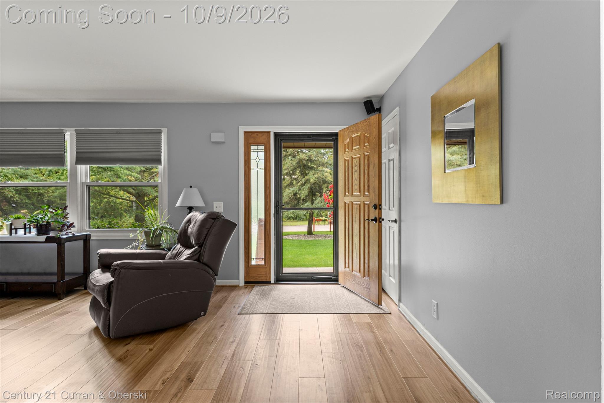 43040 Willis Road Belleville, MI 48111 - Photo 7 of 65 Hardwood-finish flooring, light gray wall paint, two large windows with roller shades, and a wood entry door with a sidelight