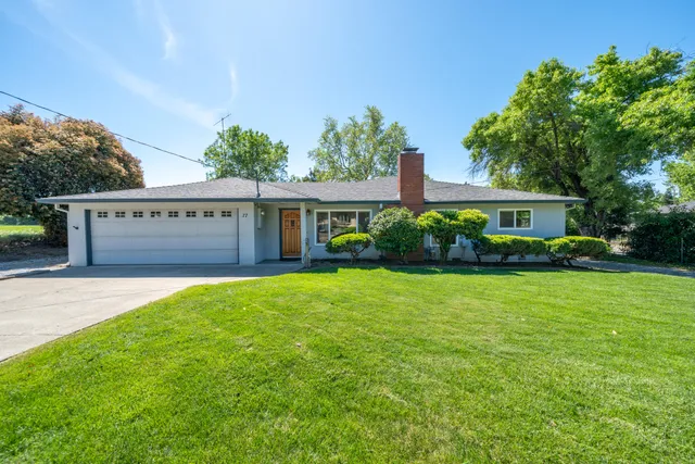 a front view of a house with a yard and potted plants