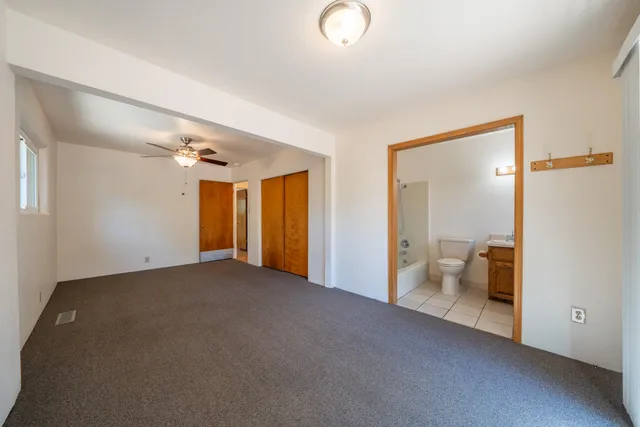 a view of an empty room with wooden floor and a ceiling fan