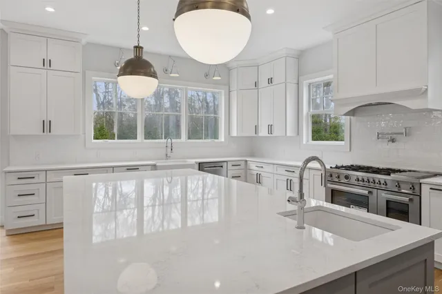 a kitchen with stainless steel appliances a sink a stove a refrigerator cabinets and a window