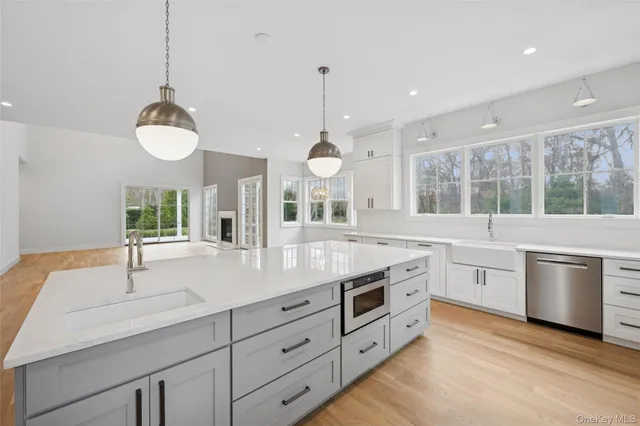 a large kitchen with kitchen island a stove a sink a center island and wooden floor