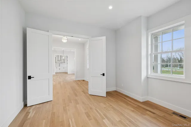 a view of empty room with wooden floor and fan