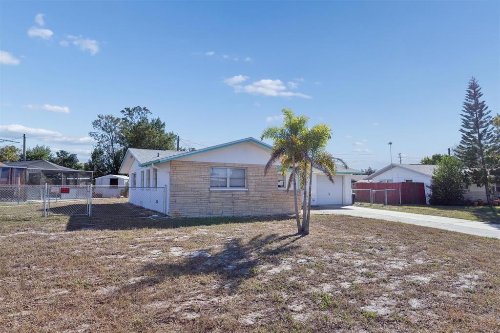 7608 Redcoat Avenue Port Richey, FL 34668 - Photo 2 of 28 a front view of a house with a yard and garage