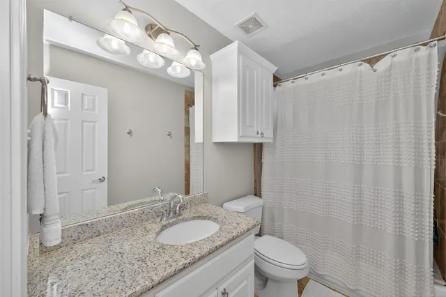 a bathroom with a granite countertop sink a toilet and a mirror