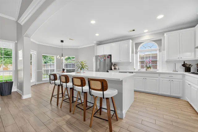 a kitchen with stainless steel appliances granite countertop a stove top oven a sink dishwasher and white cabinets with wooden floor