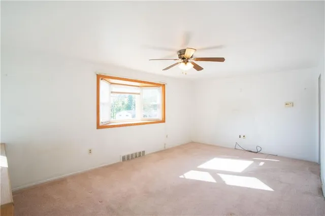 an empty room with a window and a fan