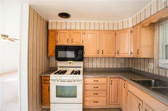 a kitchen with granite countertop a stove a sink and a refrigerator