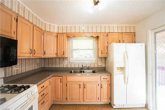 a kitchen with granite countertop a refrigerator a sink and white cabinets