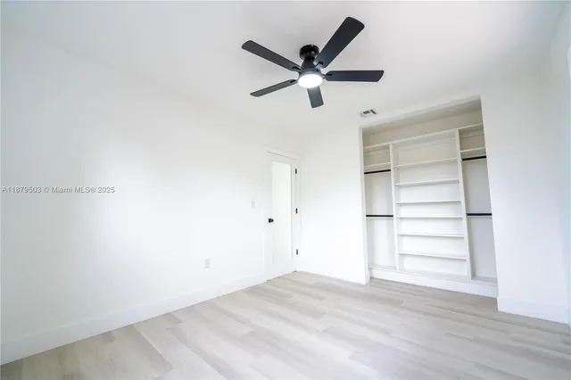 a view of a room with a ceiling fan and wooden floor