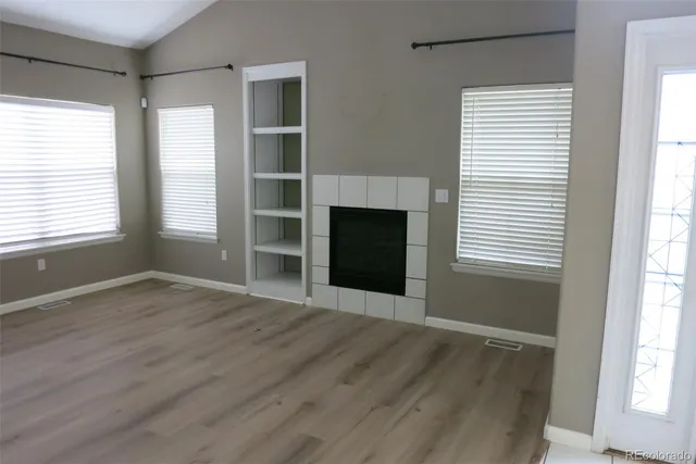 a view of an empty room with a window and wooden floor