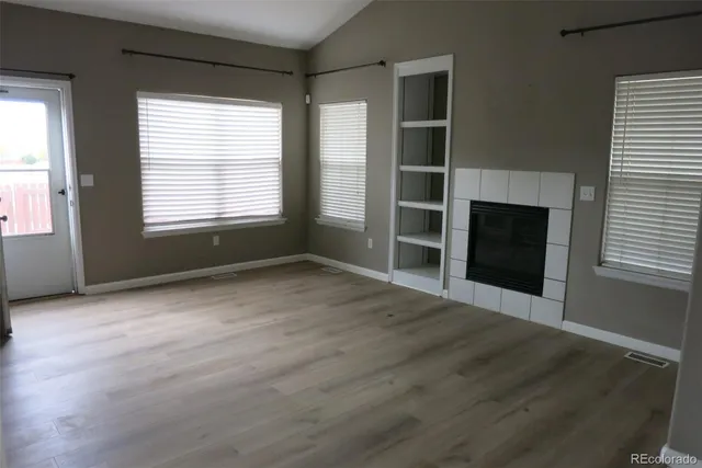 an empty room with wooden floor and windows