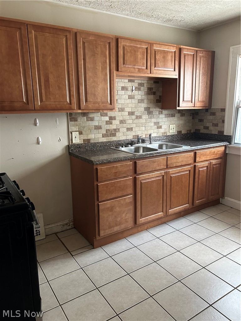 3658 Strathavon Road Cleveland, OH 44120 - Photo 14 of 16 Kitchen with range, light tile patterned floors, a textured ceiling, decorative backsplash, and sink