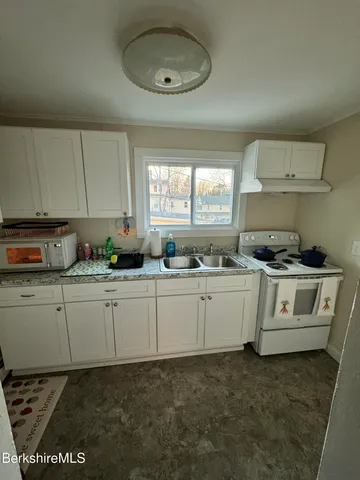 a kitchen with granite countertop white cabinets and white stainless steel appliances