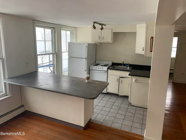 a kitchen with granite countertop a stove a sink and a refrigerator