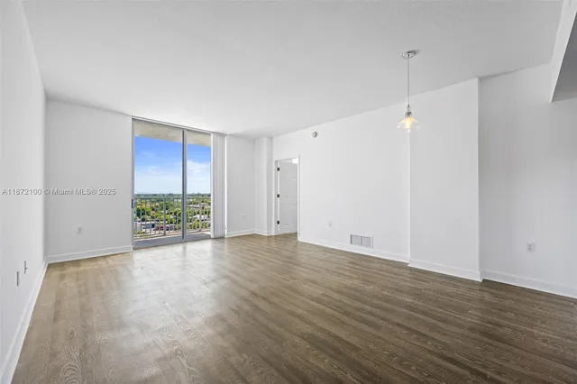 an empty room with wooden floor and window