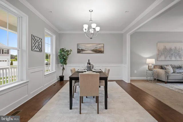 a dining room with wooden floor a chandelier a wooden table and chairs