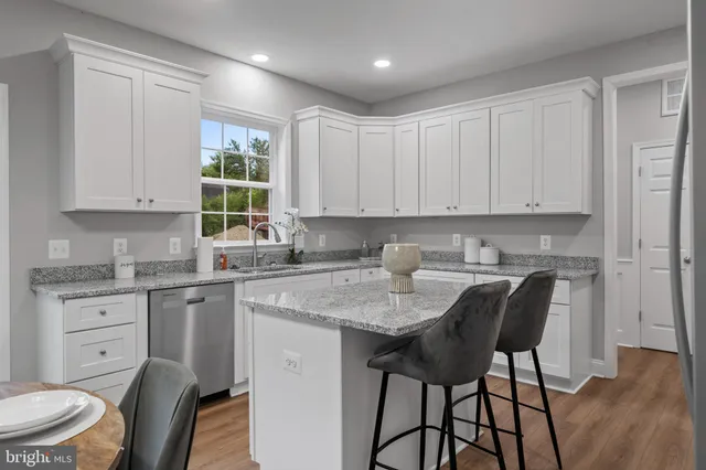 a kitchen with stainless steel appliances granite countertop a table chairs sink and cabinets