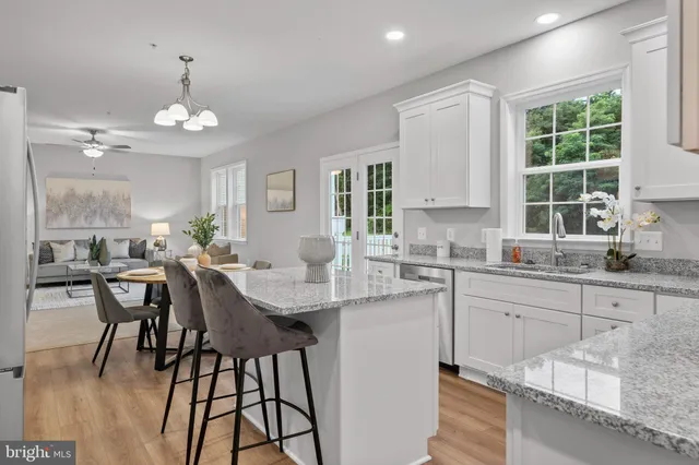 a kitchen with granite countertop a dining table chairs and white cabinets