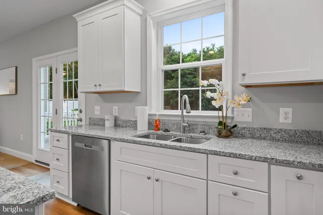 a kitchen with granite countertop a sink window and cabinets