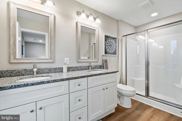 a bathroom with a granite countertop sink a toilet and a mirror