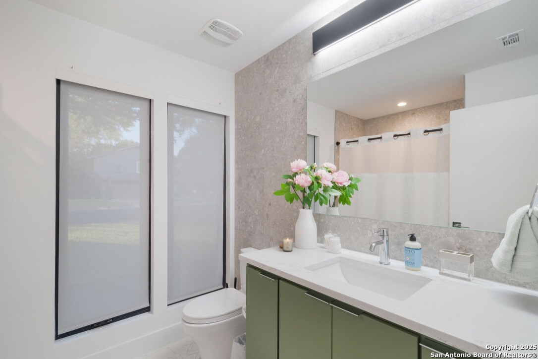 8900 Point W Drive Austin, TX 78759 - Photo 14 of 29 a bathroom with a granite countertop sink a toilet and a large mirror