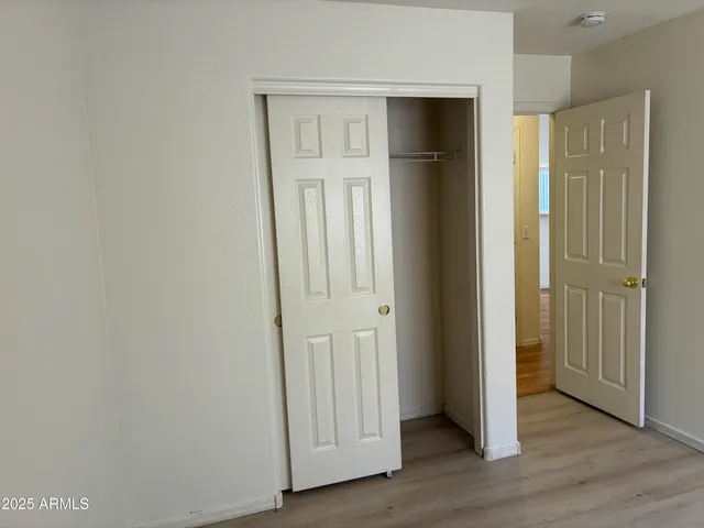 an empty room with wooden floor & closet area