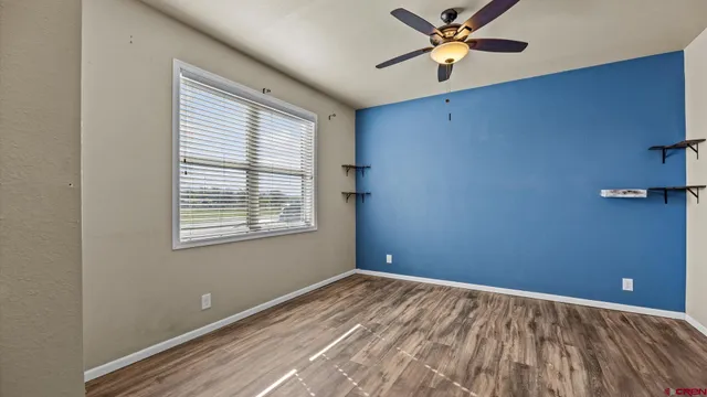 a view of an empty room with a window and a ceiling fan