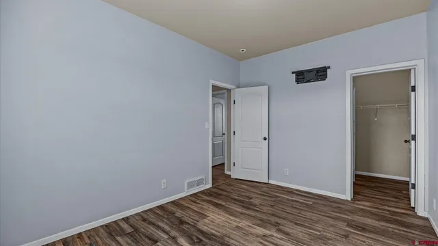 a view of an empty room with wooden floor and closet