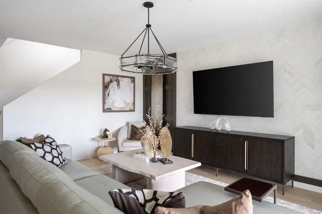 a living room with furniture a flat screen tv and a chandelier