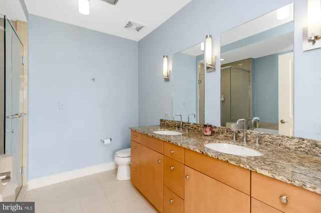 a bathroom with a granite countertop sink a toilet and a mirror