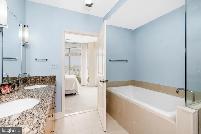 a bathroom with a granite countertop tub sink and mirror
