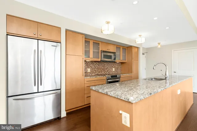 a kitchen with stainless steel appliances granite countertop a refrigerator a stove a sink cabinets and a refrigerator