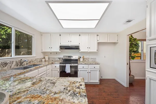 a kitchen with stainless steel appliances white cabinets a sink and a stove