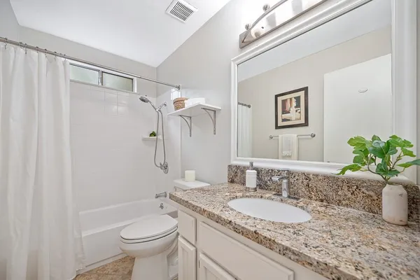 a bathroom with a granite countertop sink toilet and mirror