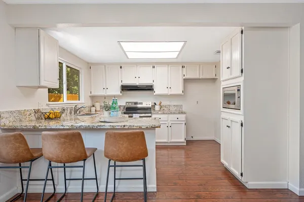 a kitchen with granite countertop white cabinets and white stainless steel appliances
