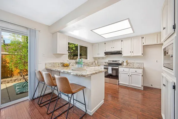 a kitchen with stainless steel appliances granite countertop a stove a sink dishwasher and a refrigerator with wooden floor