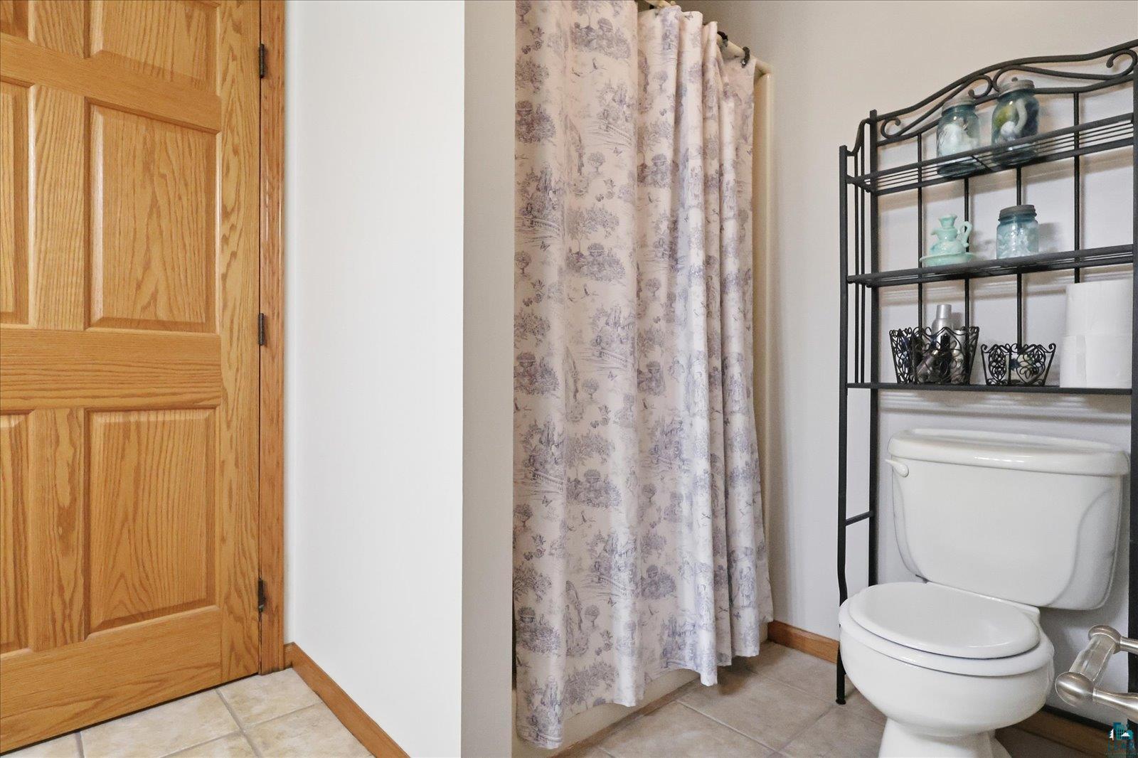 41 East Stark Road Esko, MN 55733 - Photo 9 of 19 Full bathroom featuring a white toilet, a shower with a patterned curtain, and a wall-mounted shelving unit