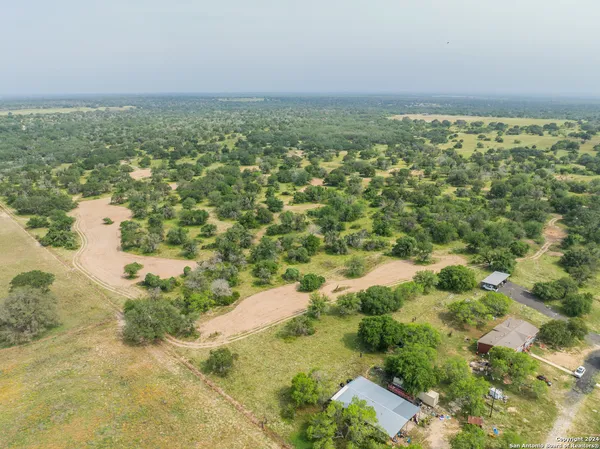 an aerial view of residential houses with outdoor space and trees