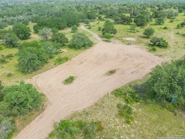 an aerial view of residential house with outdoor space and trees all around