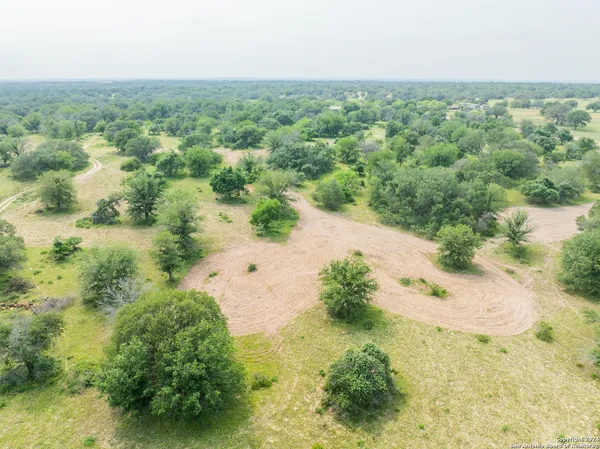 an aerial view of residential houses with outdoor space and trees