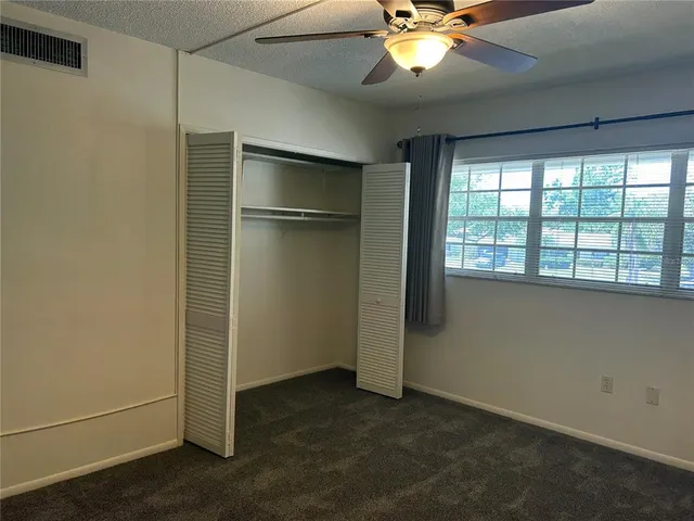 an empty room with windows and fan