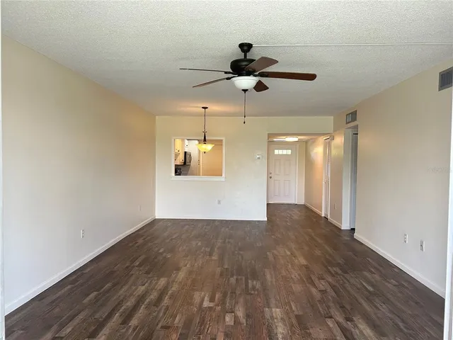a view of empty room with wooden floor and ceiling fan