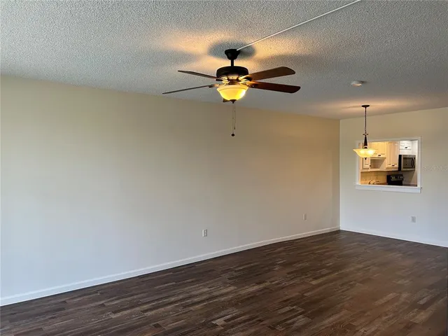 a view of a room with wooden floor and a ceiling fan