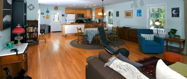 a living room with furniture kitchen view and large windows